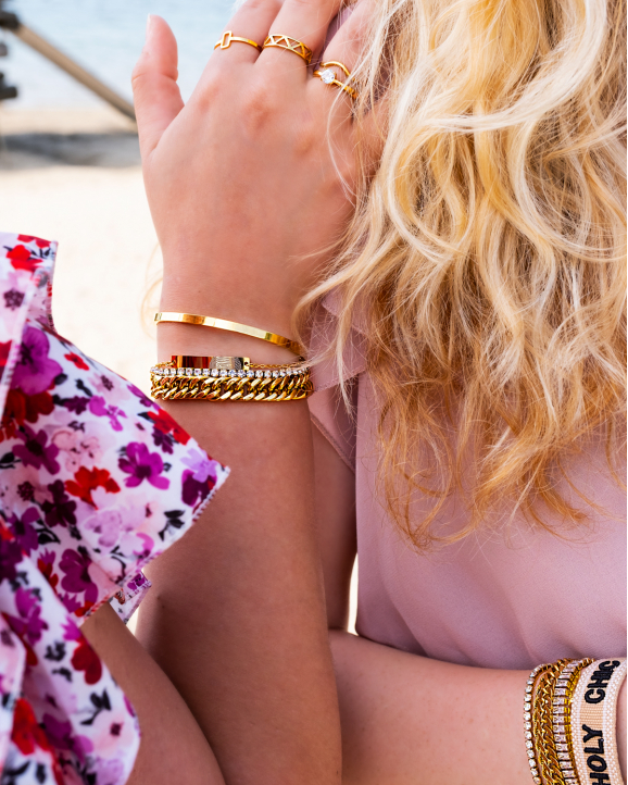 Vrouw draagt mix van mooie gouden armbanden en ringen