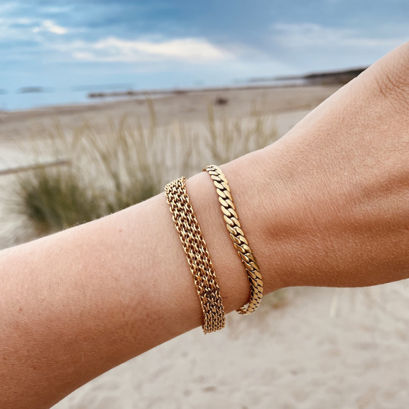 gouden armbandjes om pols bij vrouw op het strand