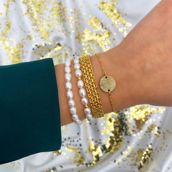 gouden armbanden met parels, mesh en vingerafdruk om pols met glitter achtergrond