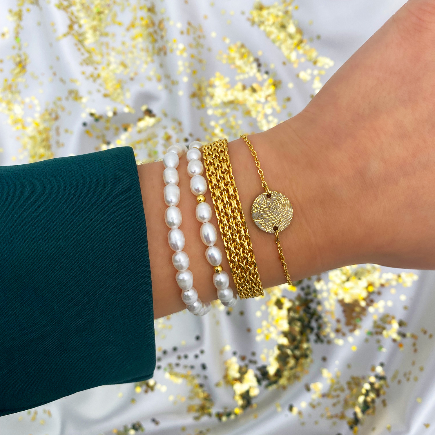 gouden armbanden met parels, mesh en vingerafdruk om pols met glitter achtergrond