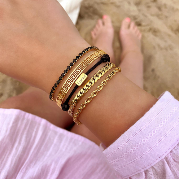 Zwarte armbandjes met gouden armbandjes gecombineerd op het strand