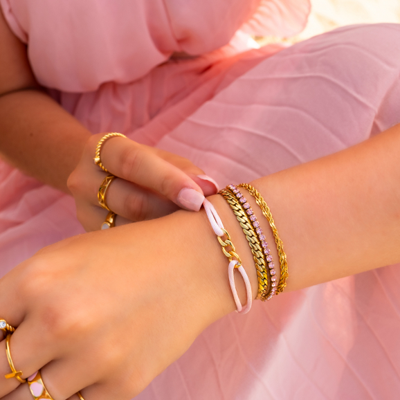 Model met roze jurk draagt goud met roze armbanden