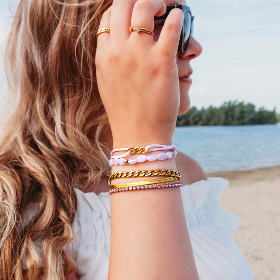 Goud met roze armbanden set op het strand
