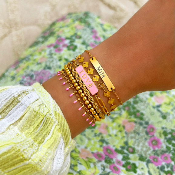 Gouden armbanden gecombineerd met roze armbandje