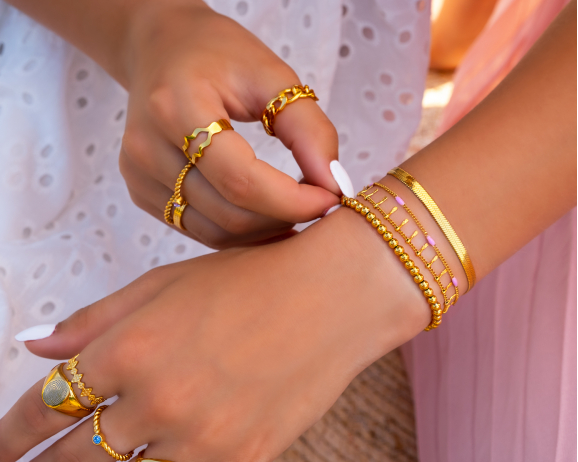 Model draagt sieradenlook met gouden armbanden en ringen