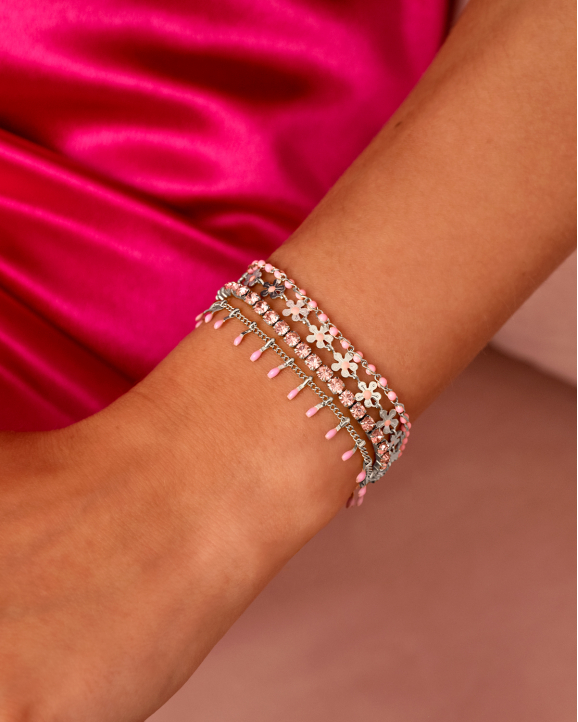 model draagt zilveren armbanden met roze details