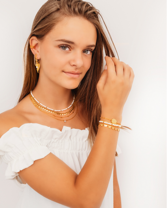 Gouden sieradenlook met witte details gedragen door model