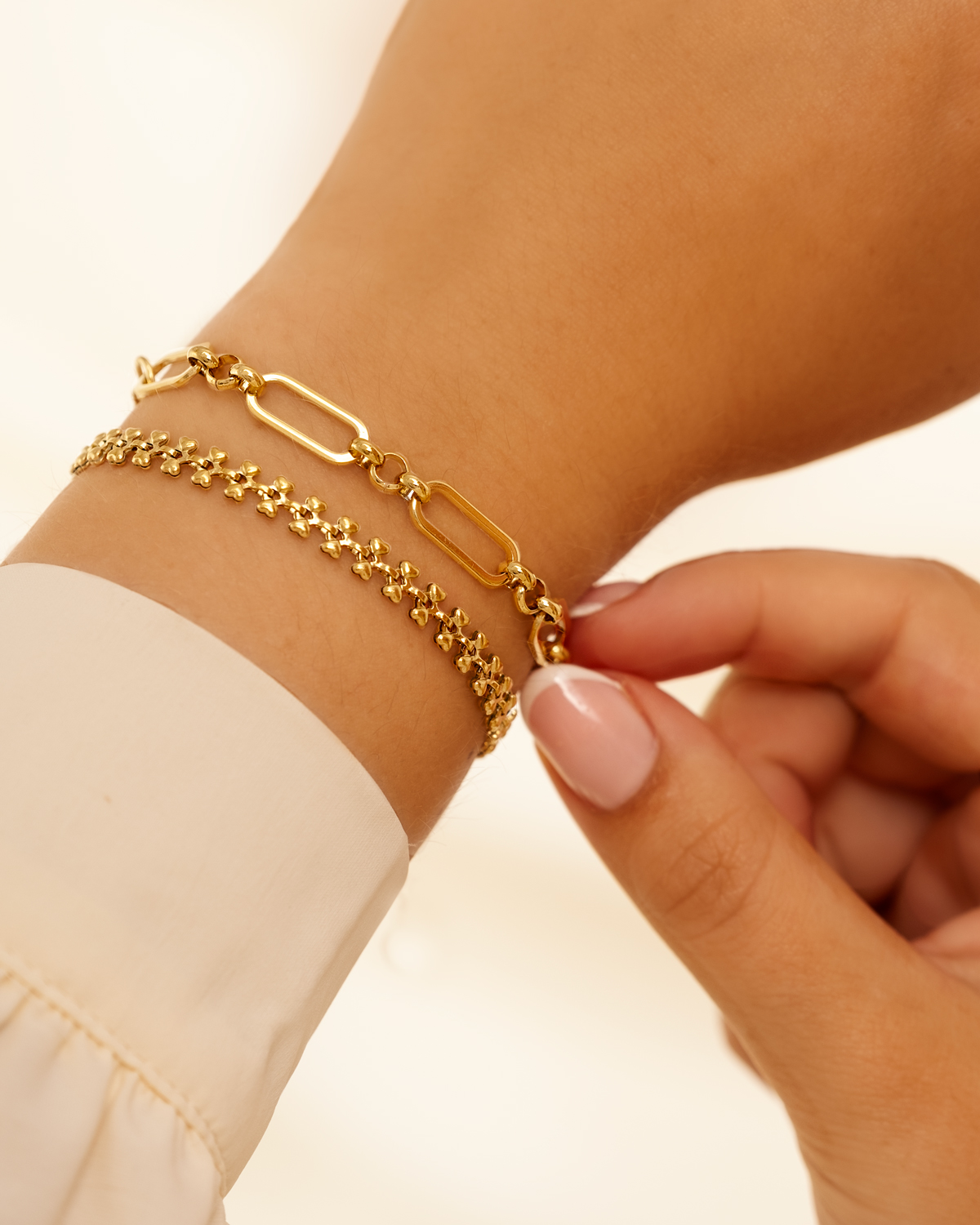 Twee gouden armbanden om pols