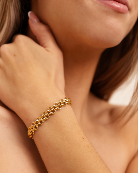 Model draagt gouden armband met chains