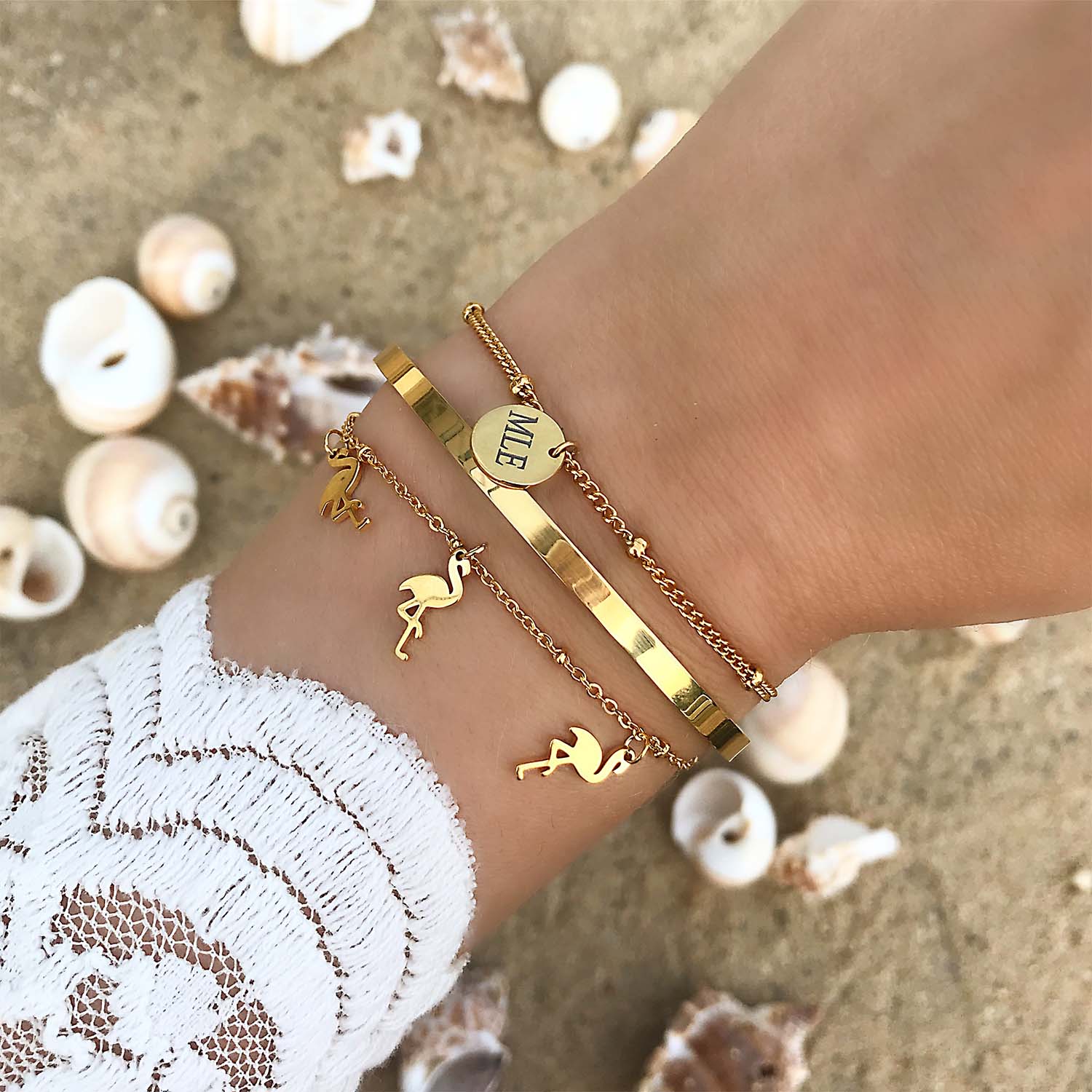 Gouden trendy armbanden om de pols op het strand met schelpen