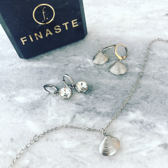 Zilveren sieraden op een marmeren plaatje met oorbellen