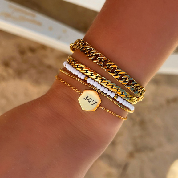 Pols met mix van mooie gouden armbanden op strand