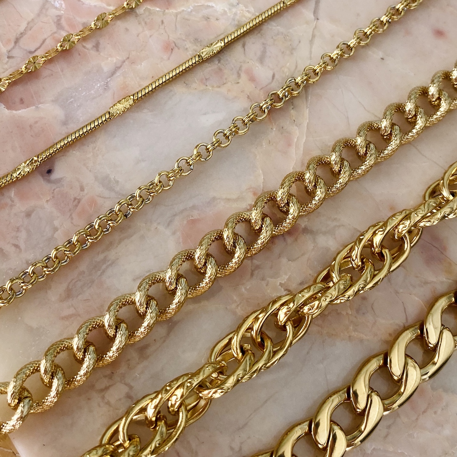 gouden schakelarmbanden op een marmer plaatje