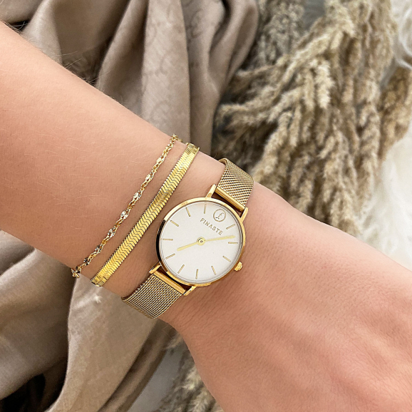 Gouden armbandjes met horloge om pols