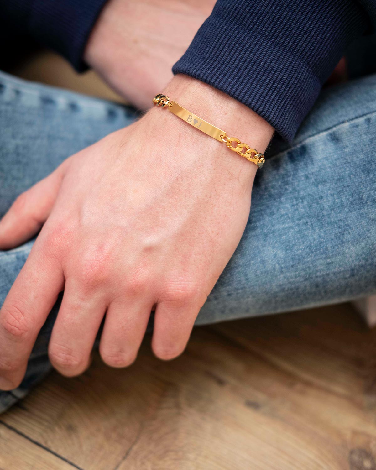 Het model draagt de goudkleurige schakelarmband voor mannen om zijn pols