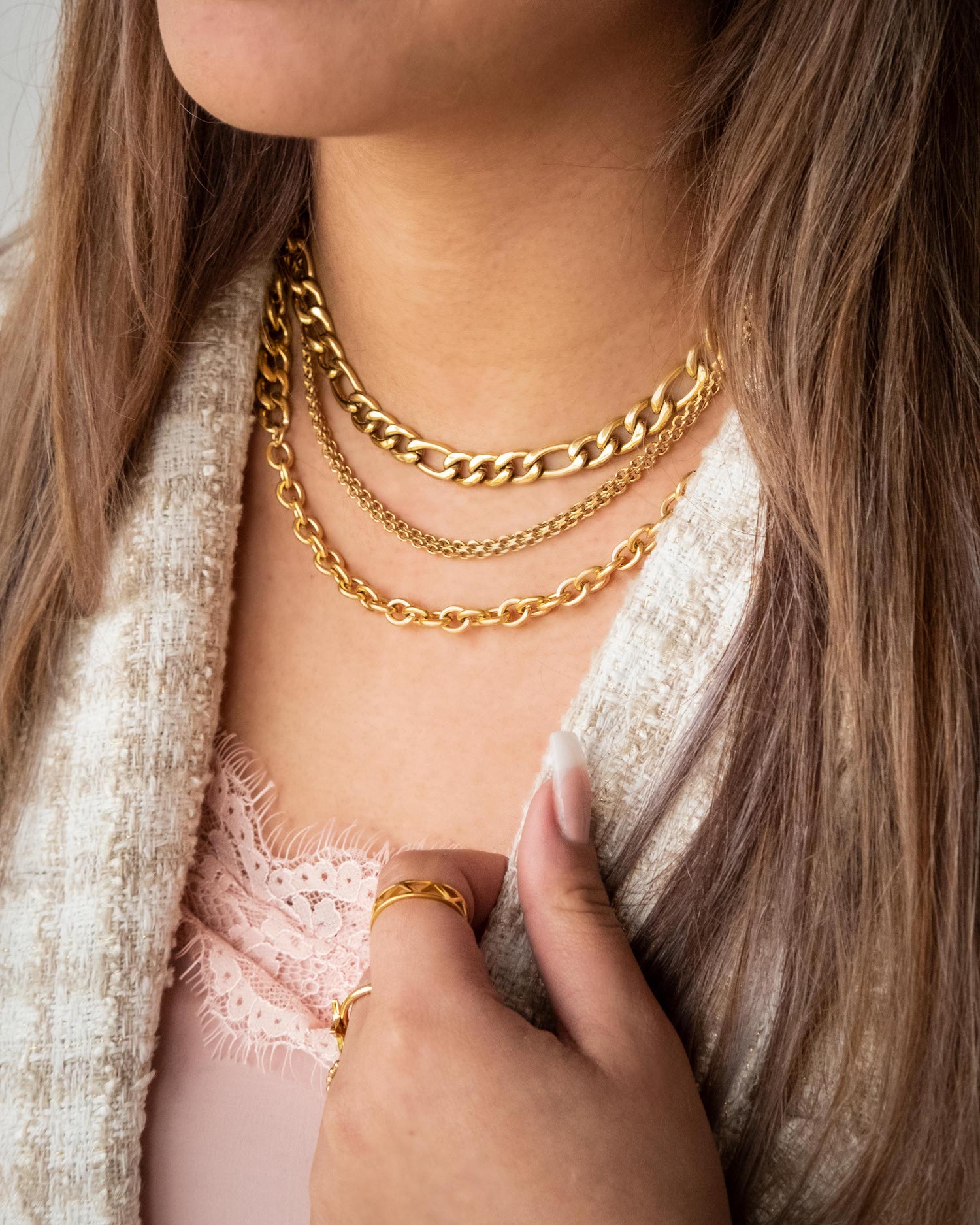 Het model draagt een necklace party van verschillende kettingen in het goud om haar hals