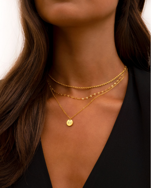 Model draagt mooie gouden necklace layer met initial ketting en dubbele ketting