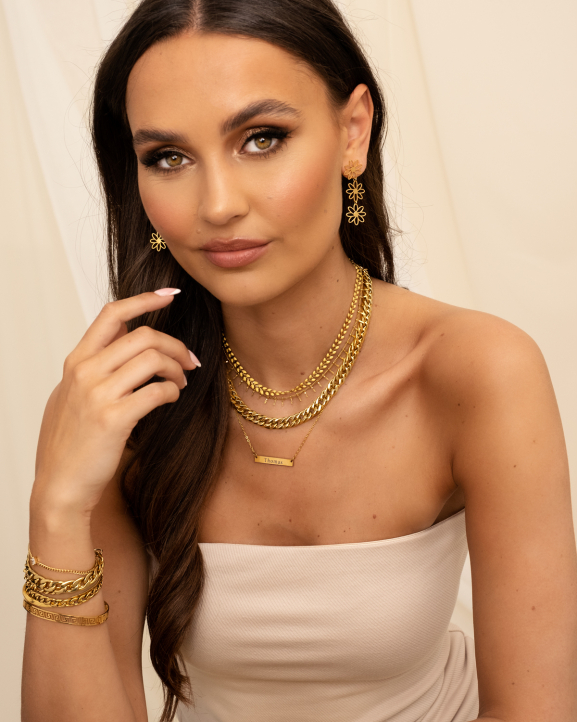 Modelfoto met gouden sieraden en ketting met graveerbare bar 