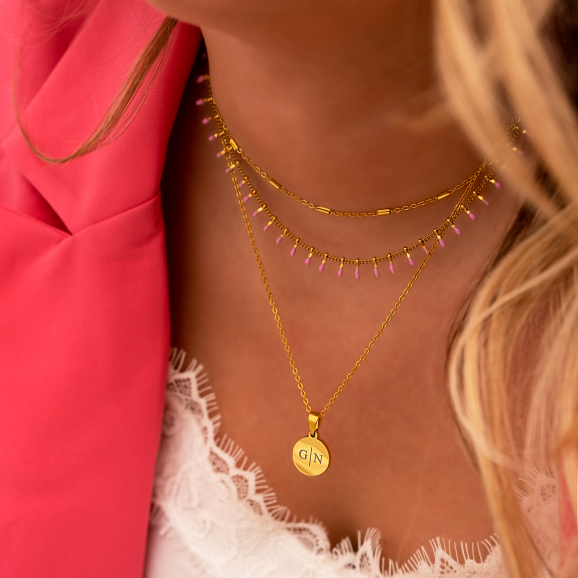 Vrouw draagt gouden necklace layer met roze details