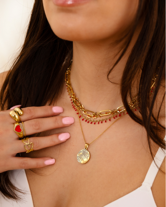 Model draagt gouden sieraden met rode details