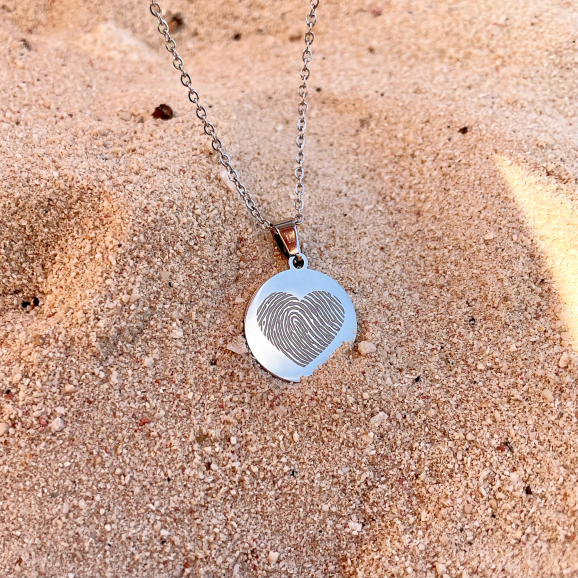 zilveren ketting met vingerafdruk gravering in de vorm van een hart in het zand