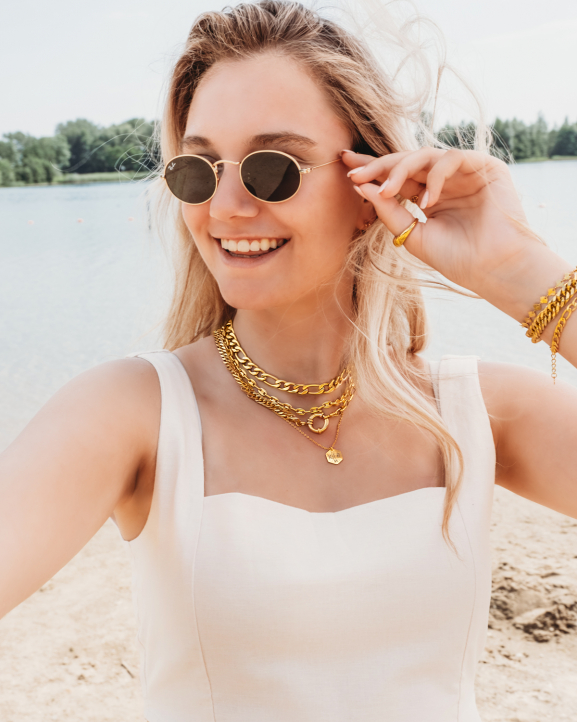 Vrouw op strand draagt mooie gouden sieraden