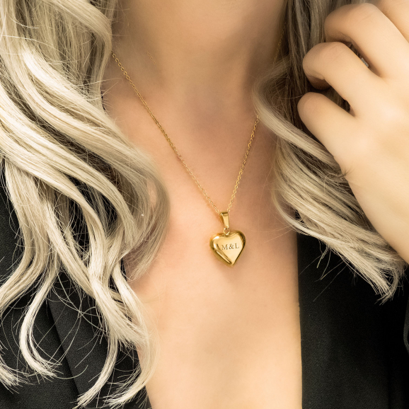 Vrouw met blonde haren draagt de gouden ketting met hart als hanger