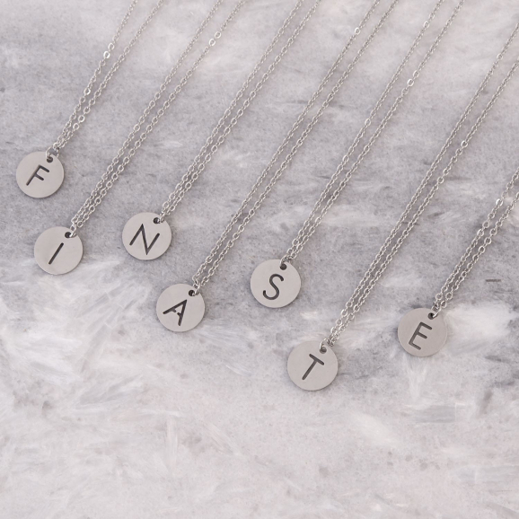 Verschillende letter kettingen in het zilver op een marmeren plaatje