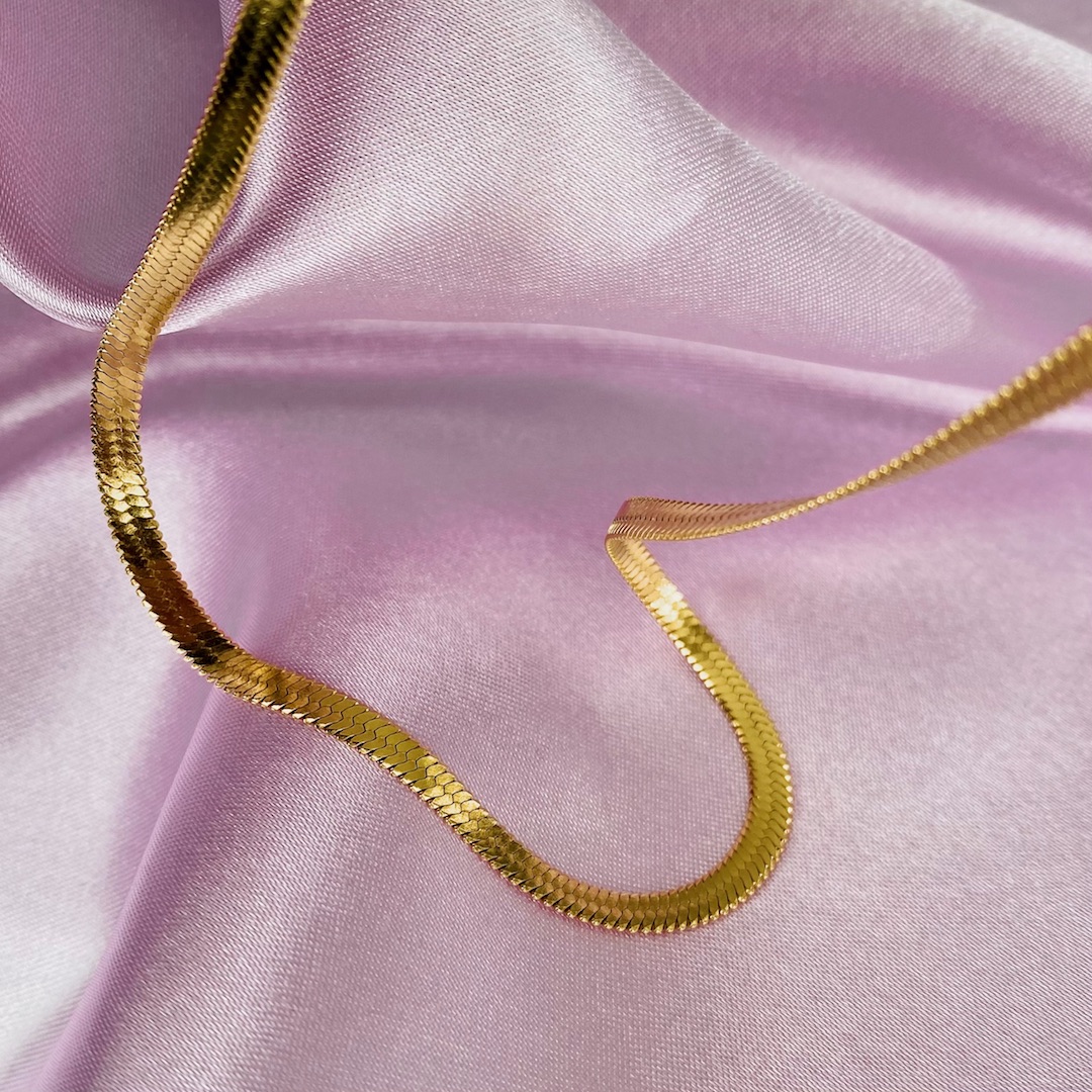 Platte gouden ketting op roze satijn