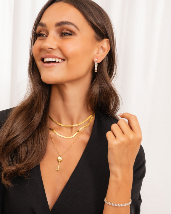 Model draagt sieradenlook met mooie gouden kettingen oorbellen en armband