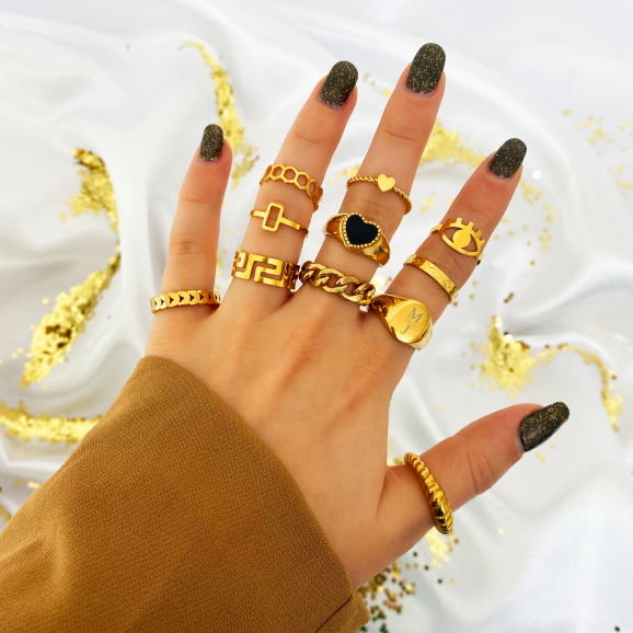 gouden sieraden om vingers van vrouw met satijnen glitter achtergrond