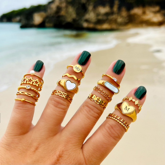 Hand met combinatie van mooie gouden ringen op strand