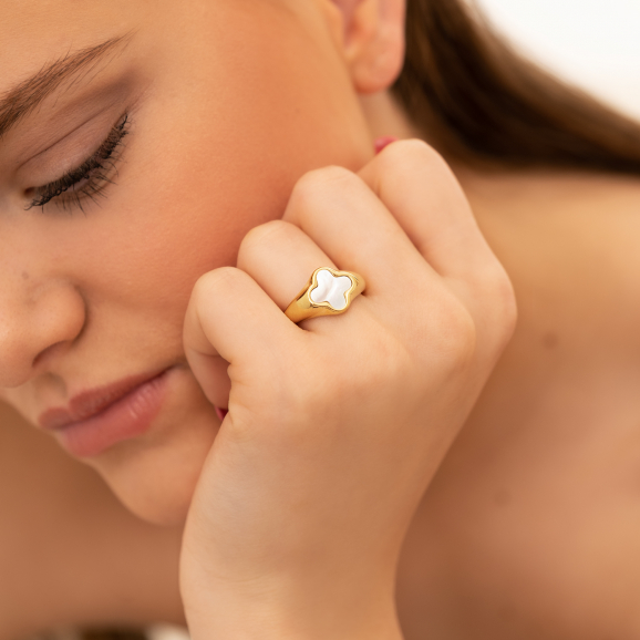 Model draagt gouden ring met parelmoer klavertje