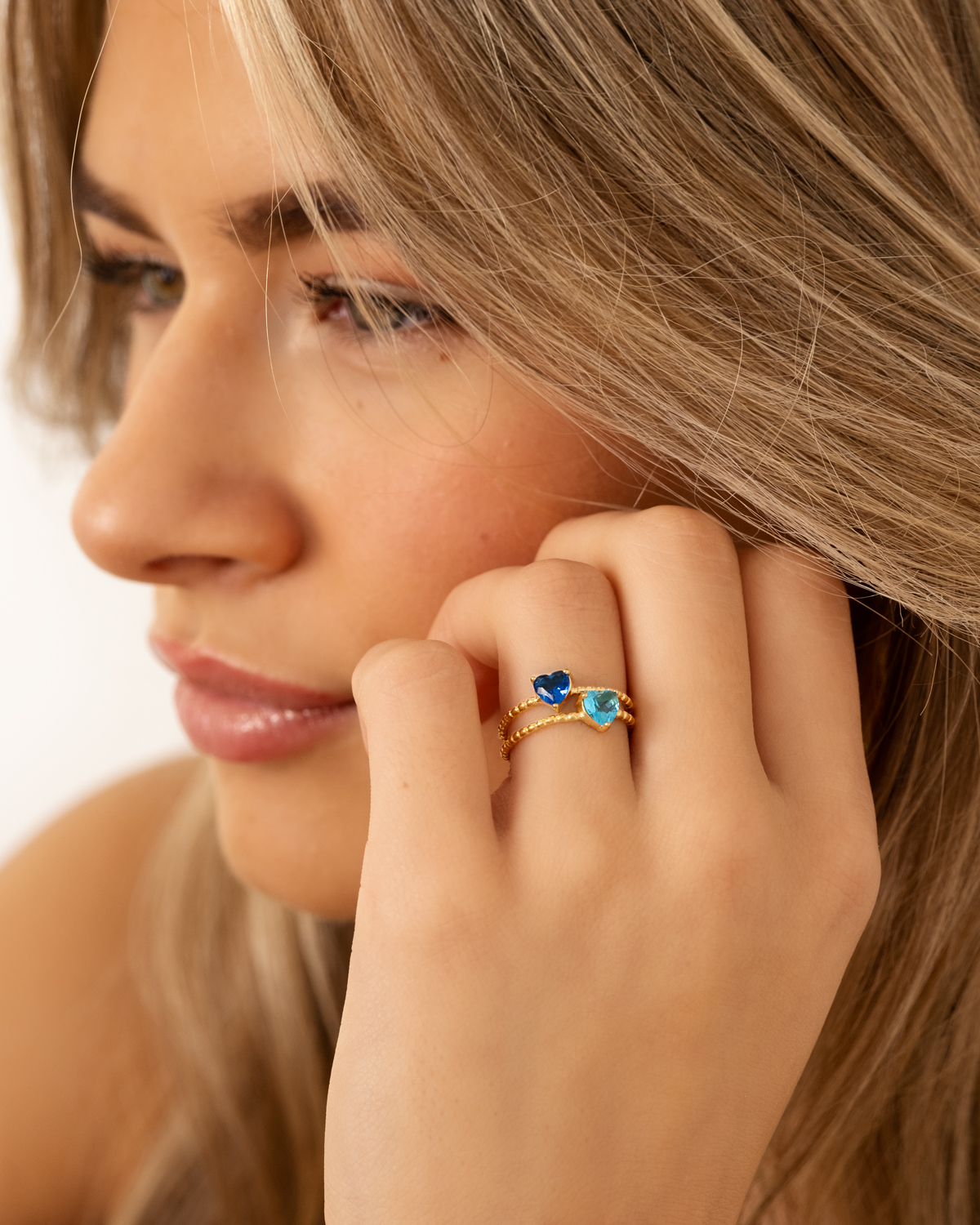 Model draagt mix van goudkleurige birthstone ringen