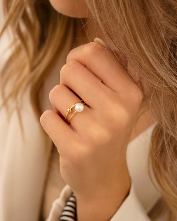 Model draagt gouden ringen met parel en bolletje