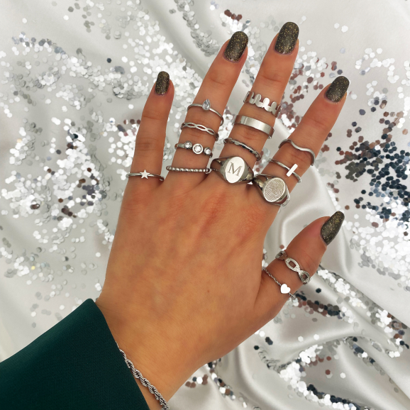 zilveren ringen mix and match om vingers van vrouw met marmeren achtergrond en initialen details