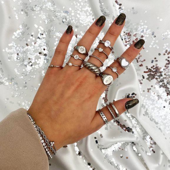 zilveren ringen om vingers vrouw met glitter achtergrond