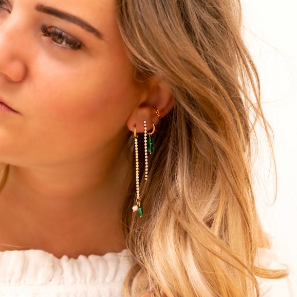 Model draagt tennis earrings met emerald en pearls
