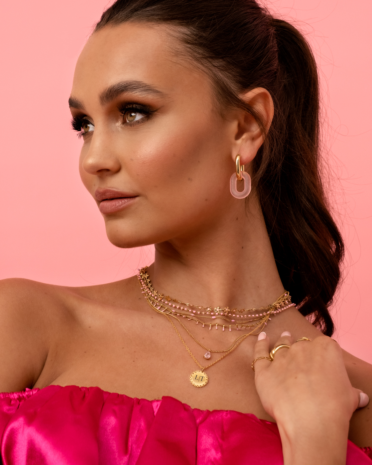 model draagt gouden sieraden met roze details