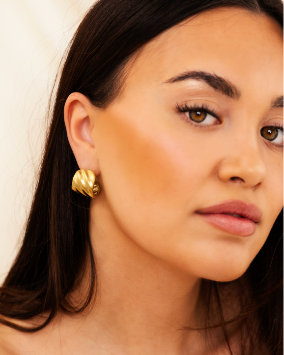Model draagt gouden bold earrings