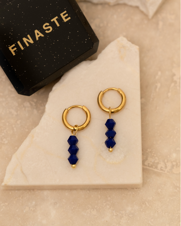 Gouden oorringetjes met blauwe steentjes in sieradendoosje