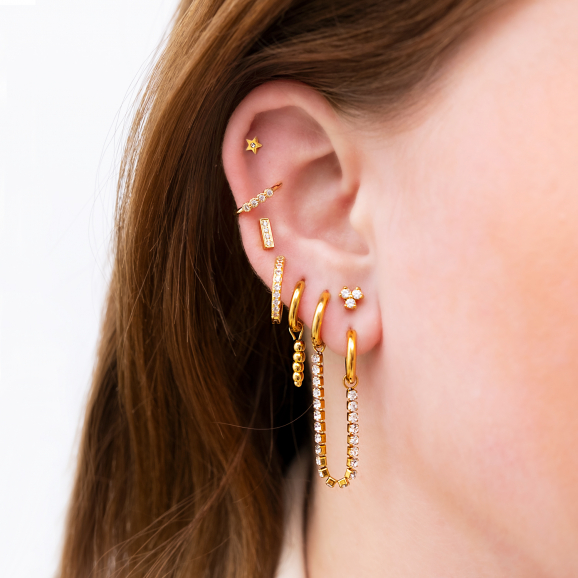 Vrouw draagt mooie gouden oorbellen in oor