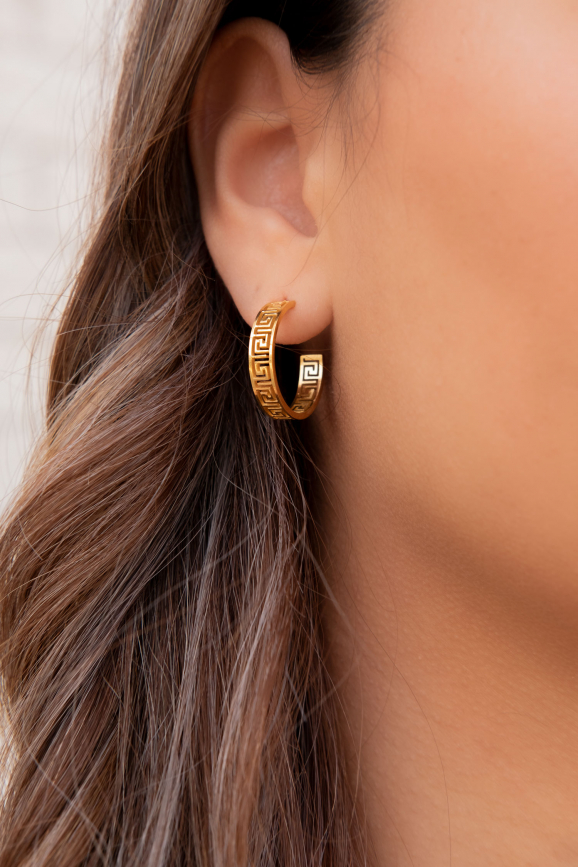 Mooie oorringen met print in het goud in het oor van het model