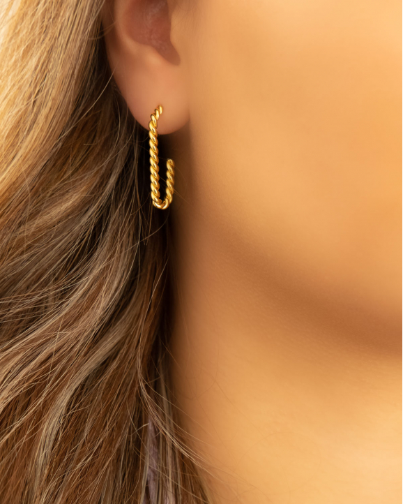 Mooie gedraaide oorringen in het goud in het oor van het model