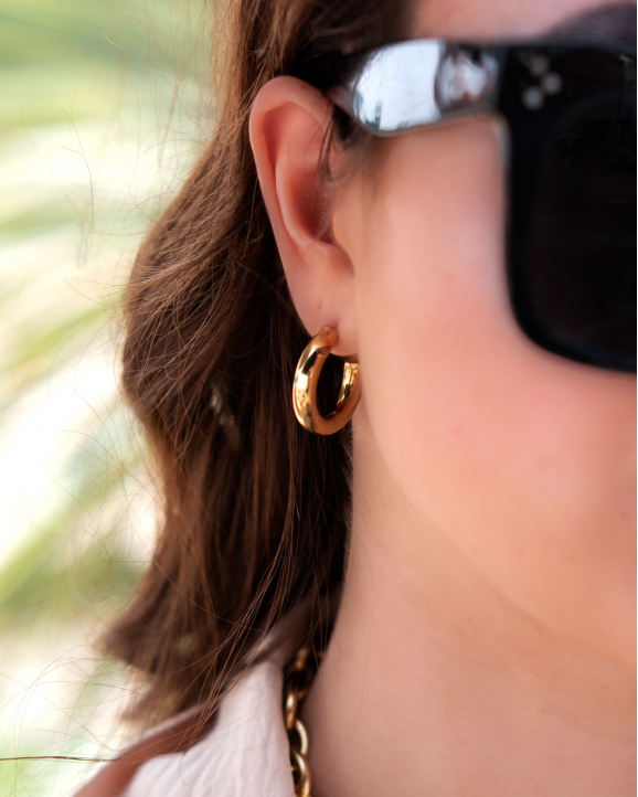 Mooie gouden creolen oorbellen in het oor van het model