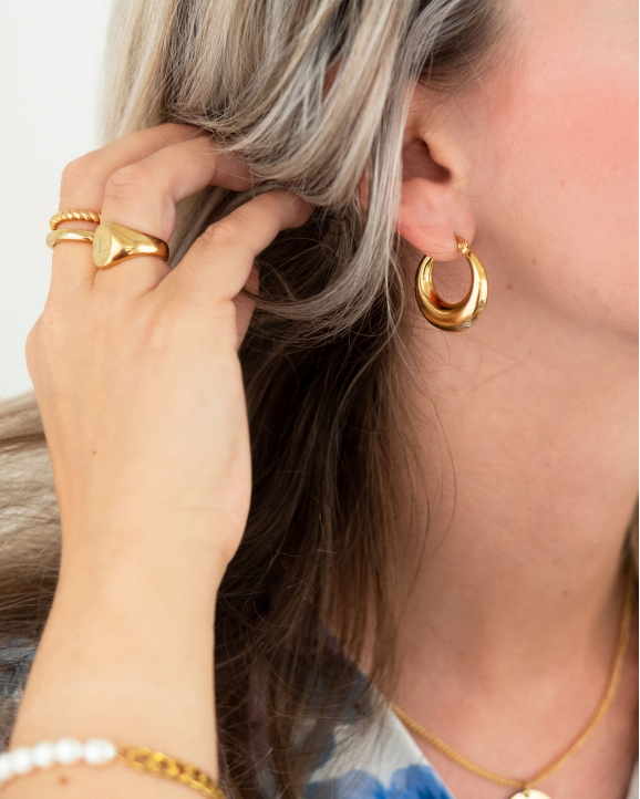 Mooie goudkleurige oorbellen creolen in het oor van het model