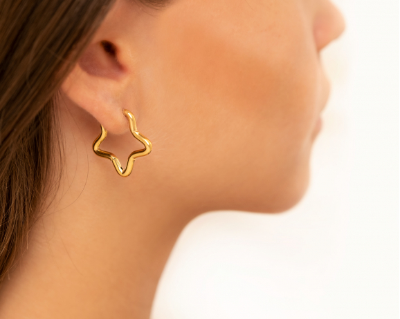 Model draagt Open star oorringen goudkleurig in oor
