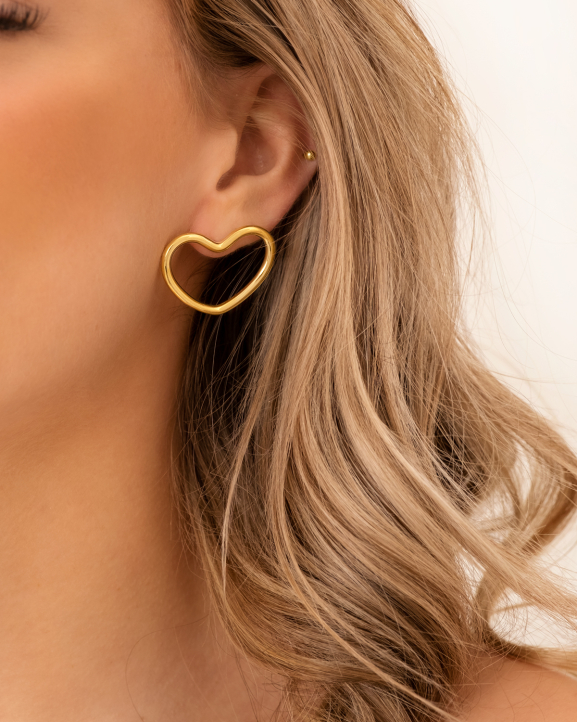 Model draagt gouden stud oorbellen met hartjes