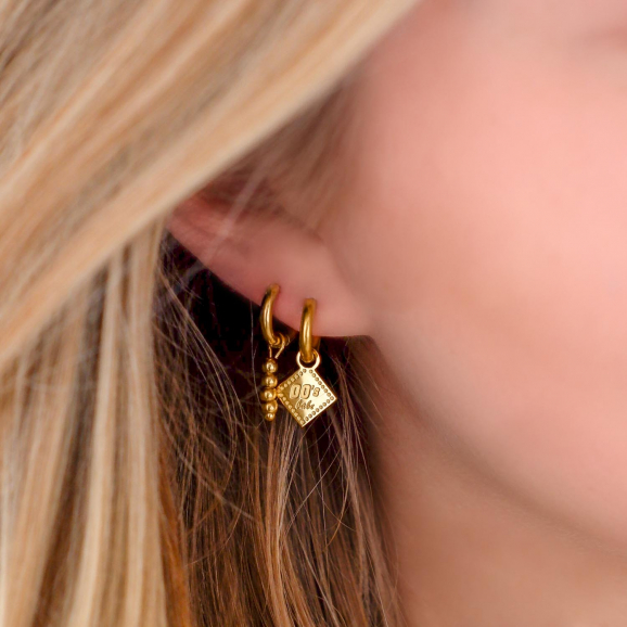 Meisje draagt mix van twee paar gouden oorbellen