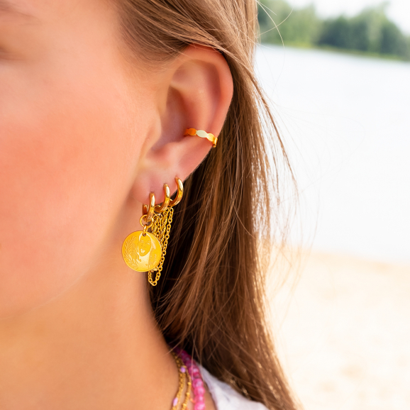 Model draagt earparty met gouden oorbellen